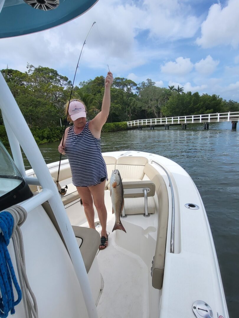 A woman holding a fishing road with a fish