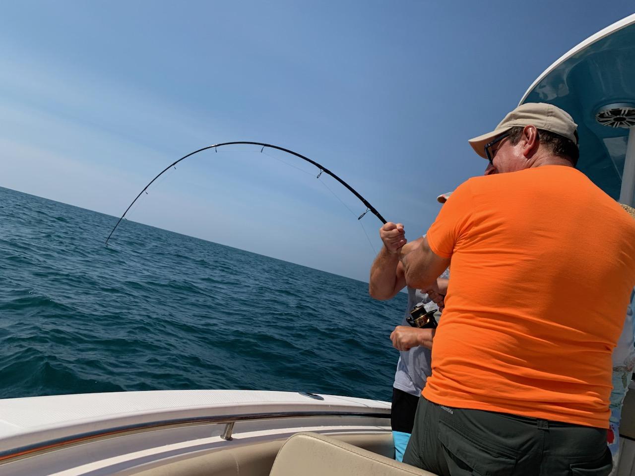 A man fishing on the ocean while sitting in a boat.